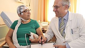 A doctor talks to a patient in a hospital room.