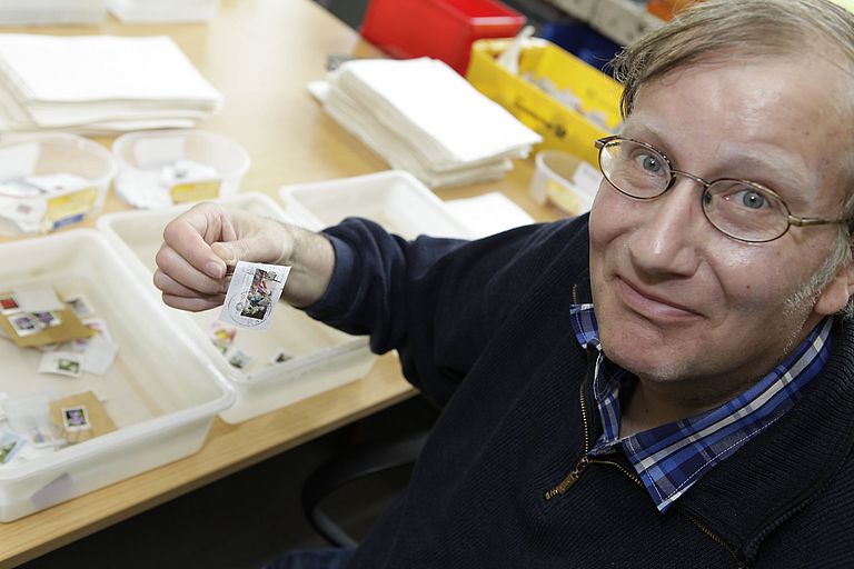 Mann sortiert Briefmarken
