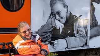 Mareike Maneke sitzt vor der Bethel-Bahn, auf der ein Bild von ihr zu sehen ist