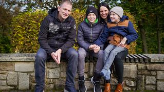 Familie Becker sitzt auf einer Mauer im Garten des Kinder- und Jugendhospizes