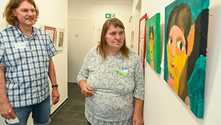 Jens Köhl freut sich, dass Gisela Ebel wieder regelmäßig die Malwerkstatt im Begegnungszentrum besucht. Die Bilder der Teilnehmenden sind auf dem Flur ausgestellt. 