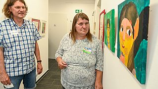 Jens Köhl freut sich, dass Gisela Ebel wieder regelmäßig die Malwerkstatt im Begegnungszentrum besucht. Die Bilder der Teilnehmenden sind auf dem Flur ausgestellt. 