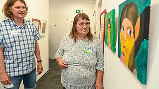 Jens Köhl freut sich, dass Gisela Ebel wieder regelmäßig die Malwerkstatt im Begegnungszentrum besucht. Die Bilder der Teilnehmenden sind auf dem Flur ausgestellt.