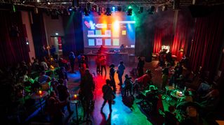 Disco-Besucherinnen und Besucher tanzen im bunten Scheinwerferlicht. 