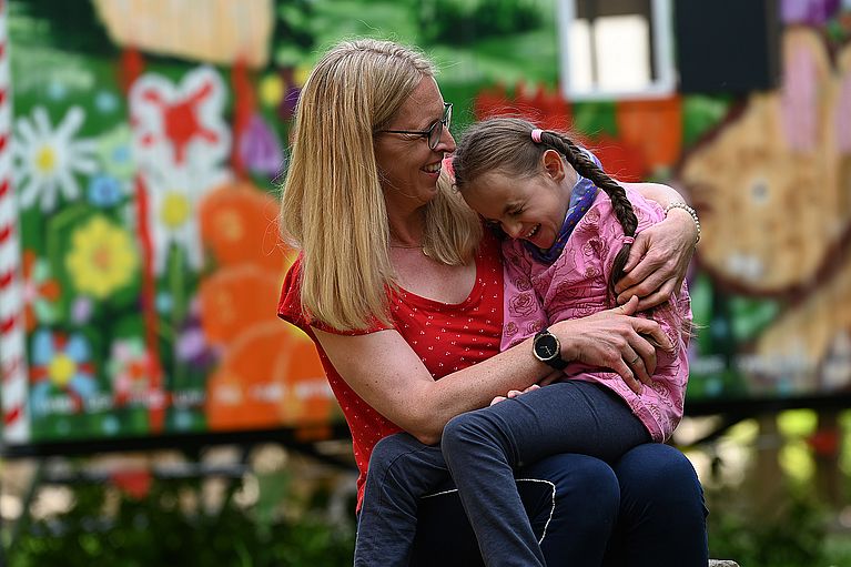 Frau hält Mädchen im Arm.