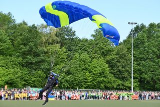 Ein Fallschirmspringer landet auf dem Rasen auf dem Sportplatz