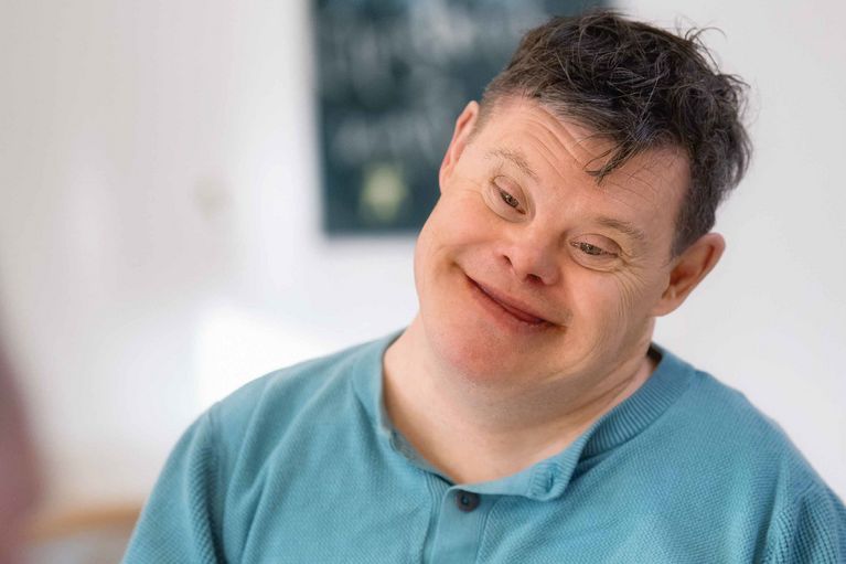 Ein Mann hält den Kopf schräg und lächelt in die Kamera
