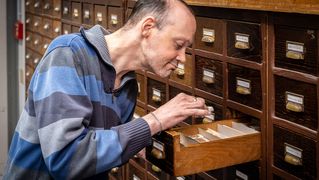 Carsten Hirsch holt ein Bündel Briefmarken aus einer Schublade.