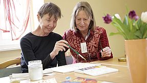 Employee helps a woman to paint.