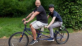 Mitarbeiter und Klient fahren Tandem.