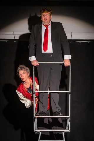 Ein Schauspieler mit Krone steht auf einer Leiter.