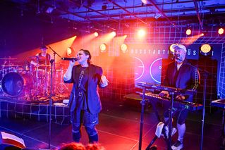 Die Sängerin und der Keyboarder singen auf der Bühne im roten Scheinwerferlicht.