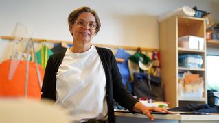 Anke Burre steht an einem Tisch und blickt in die Kamera