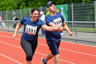 Eine Frau und ein Mann beim Firmenlauf auf der Laufbahn.