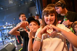 Kinder im Publikum formen mit Händen ein Herz