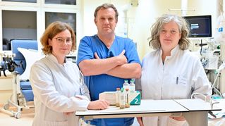 Drei EvKB Mitarbeitende stehen in einem Patientenzimmer.