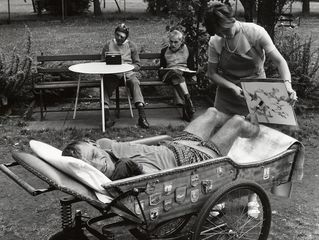 Ein Mann sitzt in einem Rollstuhl und malt mit seinen Füßen.