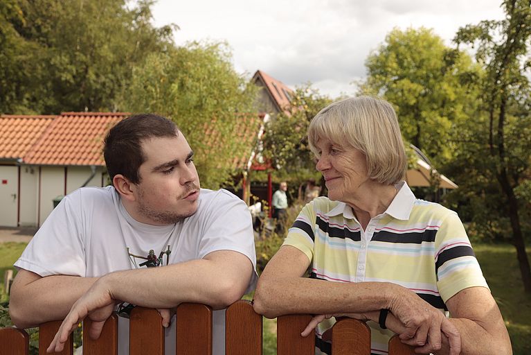 Mann und Frau am Zaun im Schrebergarten