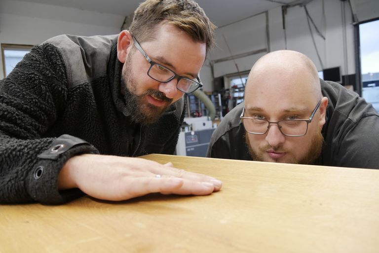 Daniel Heinzmann und Philip Fengler schauen sich ein Stück Holz an.