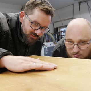Daniel Heinzmann und Philip Fengler schauen sich ein Stück Holz an.