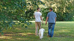 Two people walking a dog.