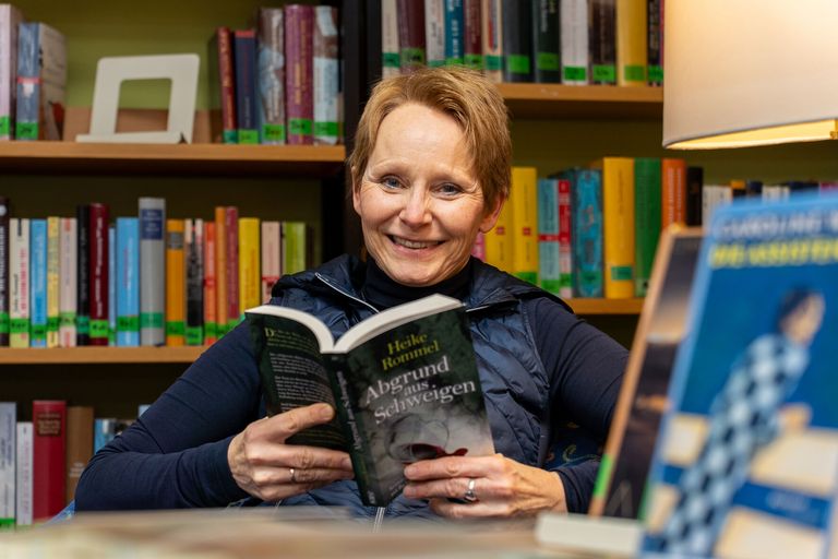 Frau hält ein Buch und lächelt.