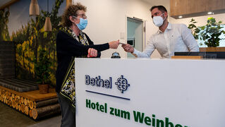 Thisabe Alfter, erster Gast des neuen Bethel Hotel zum Weinberg, bekommt von Empfangsleiter Sascha Wolter die Karte für ihr Zimmer.