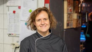 Sonja Schüler stands in the kitchen and smiles at the camera.