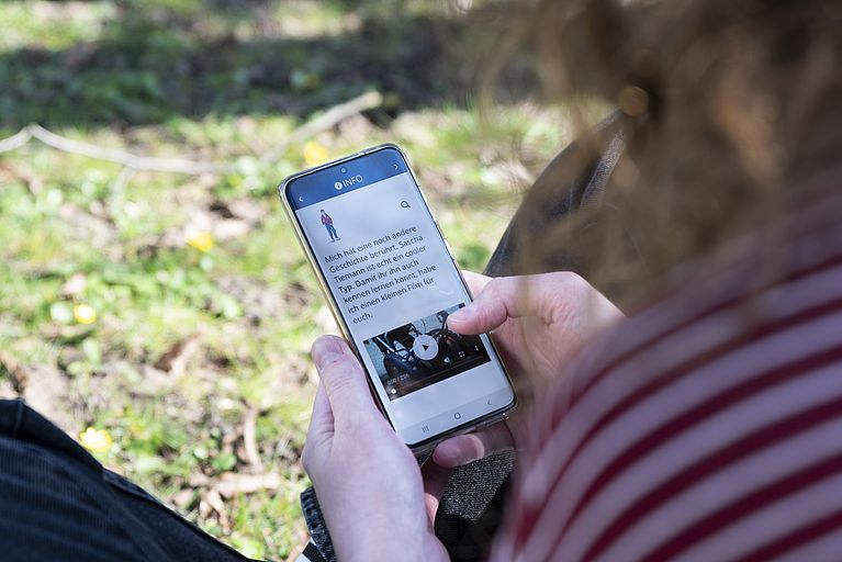 Frau nutzt mit dem Smartphone die App.