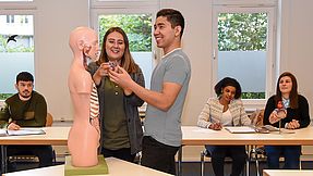 Trainees show the class something on the anatomical model.