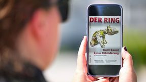 A person wearing sunglasses is holding a smartphone displaying the digital June issue of DER RING