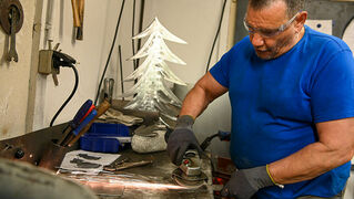 Heinz Eis works on a piece of sheet metal with the grinding machine.