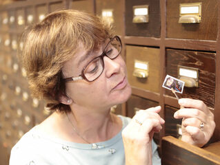 Frau betrachtet Briefmarke in der Briefmarkenstelle Bethel