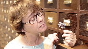 Frau betrachtet Briefmarke in der Briefmarkenstelle Bethel