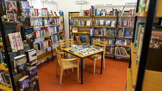Blick in den Raum der Bücherei. Ein Raum zum Verweilen mit vielen gefüllten Bücherregalen.