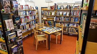 Blick in den Raum der Bücherei. Ein Raum zum Verweilen mit vielen gefüllten Bücherregalen.