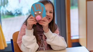 Ein Mädchen hält eine Rentierfigur in die Kamera.