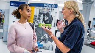 Eine Mitarbeiterin informiert eine junge Frau an einem Stand.