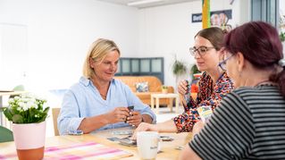 Three women are sitting at a table playing cards.