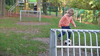 Junge spielt Fußball im Garten der Kinder- und Jugendpsychiatrie