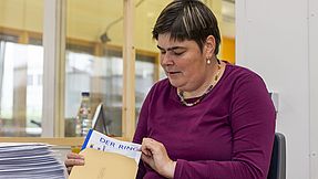 Beschäftigte packt die Zeitschrift in einen Postumschlag.