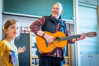 Wolfgang Spode spielt fröhlich Gitarre.