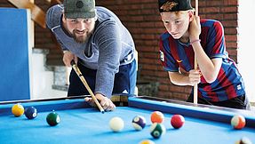 Mitarbeiter spielt mit Jungen Billard.