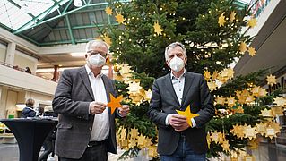 Pastor Ulrich Pohl und Rektor Prof. Dr.-Ing. Gerhard Sagerer stehen vor dem Weihnachtsbaum.