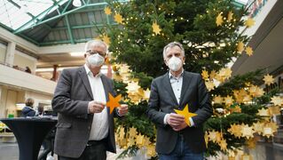 Pastor Ulrich Pohl und Rektor Prof. Dr.-Ing. Gerhard Sagerer stehen vor dem Weihnachtsbaum.