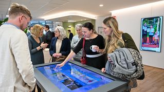 Mehrere Personen stehen an einem digitalen Tisch.