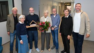 Gruppenbild: Leitende übergeben Blumenstrauß