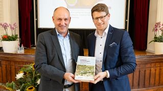 Dr. Simon Stark und Professor Dr. Martin Holtkamp halten das Bethel-Buch hoch.
