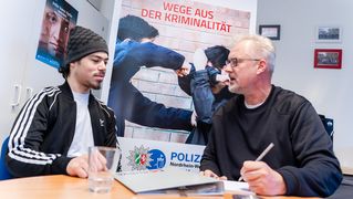 Zwei Männer unterhalten sich an einem Tisch.