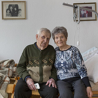 Heinz und Brigitte Müller sitzen auf ihrem Bett.